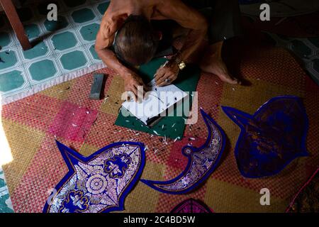 Kite malais travaillant sur un kite dans son atelier en basse lumière. Banque D'Images