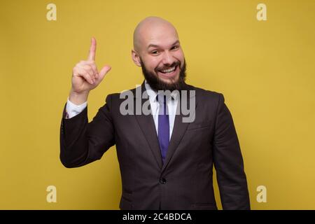 Jeune caucasien avec la barbe portant le costume homme pointant vers le haut. Banque D'Images