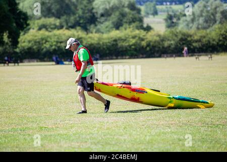 25 juin 2020Teston Bridge Country Park. Le jour le plus chaud de l'année jusqu'à présent. Un homme tire un canot sur l'herbe jusqu'à la rivière Medway. Banque D'Images