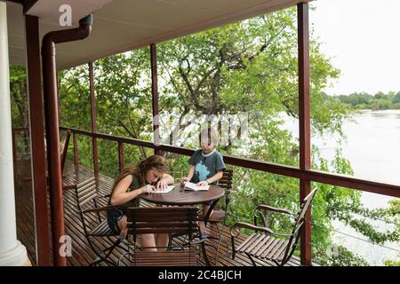 Deux enfants s'y dressent sur une table sur une terrasse surplombant une rivière large. Banque D'Images