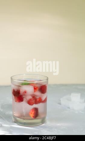 Limonade aux fraises congelées maison avec glaçons et une branche de menthe sur fond gris. Une boisson rafraîchissante en été. Copier l'espace. Orientation verticale Banque D'Images