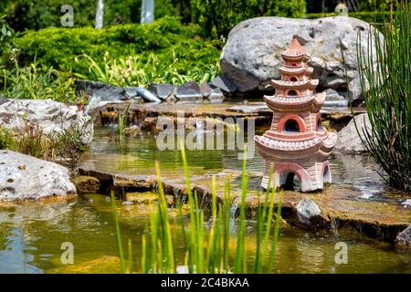 Étang artificiel avec cascade et une sculpture d'une maison japonaise dans l'eau. Banque D'Images