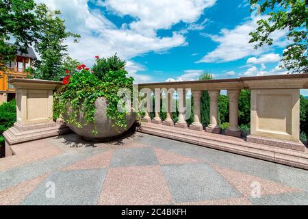 pot de fleurs en pierre sur la terrasse avec balustrades et balustrades en arrière-plan arbres verts et un ciel bleu avec des nuages par jour ensoleillé. Banque D'Images