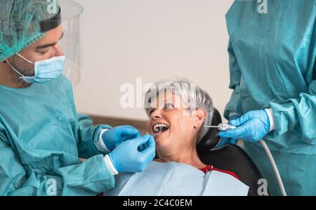 Homme dentiste exploitant femme senior en clinique dentaire - concept d'aide de soins dentaires Banque D'Images