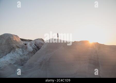 Homme explorant la plage de Sarakiniko à Milos, Grèce au coucher du soleil Banque D'Images