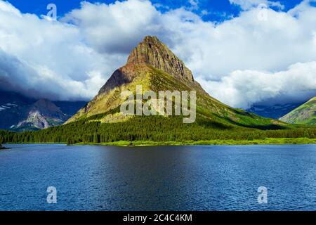 5043 Nuageux matin au lac SwiftCurrent avec Grinnell point baigné au soleil au parc national Glacier, Montana Banque D'Images