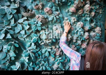 Un touriste examine les détails de la création de Gaudi à l'entrée de la Sagrada Familia Banque D'Images