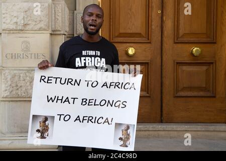 Londres, Royaume-Uni. 25 juin 2020. Un manifestant tenant une bannière pendant la manifestation.des manifestants des "Africains de la diaspora" se rassemblent devant Christie's pour exiger le retour d'objets africains. Les musées européens luttent pour garder les objets d'art africains sous la pression des militants. Crédit : SOPA Images Limited/Alamy Live News Banque D'Images