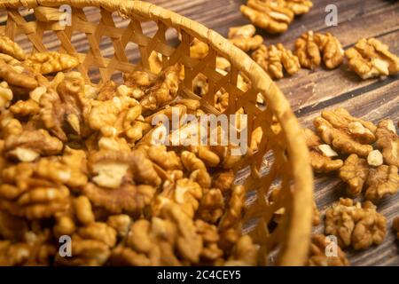 Noix pelées dans un panier en osier et noix pelées éparpillées sur une table en bois. Une alimentation saine. Régime de remise en forme. Gros plan Banque D'Images