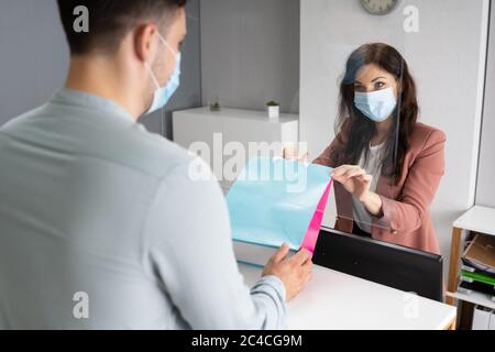 Le caissier dans la boutique ou le magasin au comptoir porte un masque facial Banque D'Images