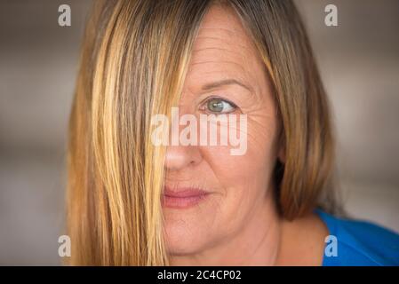 Portrait femme attrayante avec des cheveux de brunette couvrant la moitié du visage, un oeil confiant look, arrière-plan flou. Banque D'Images