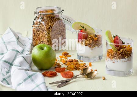 Deux portions dans des tasses transparentes de granola maison avec yaourt, noix et fruits secs Banque D'Images