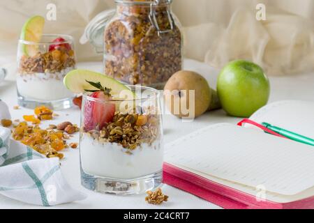 Deux portions dans des tasses transparentes de granola maison avec yaourt, noix et fruits secs Banque D'Images