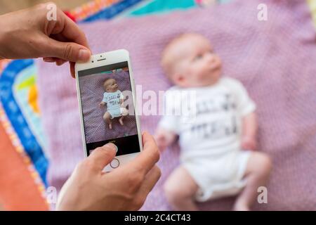 La main d'une femme prend des photos d'un nouveau-né garçon à l'aide d'un téléphone portable. Photo de Sam Mellish Banque D'Images