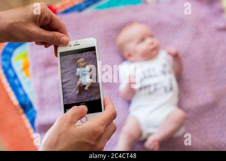 La main d'une femme prend des photos d'un nouveau-né garçon à l'aide d'un téléphone portable. Photo de Sam Mellish Banque D'Images