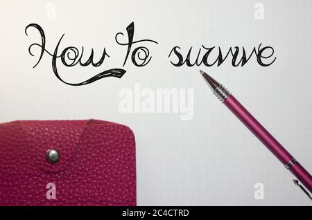 Stylo écrivant les mots Comment survivre et portefeuille en cuir. Question de faible revenu, comment survivre avec peu d'argent concept Banque D'Images