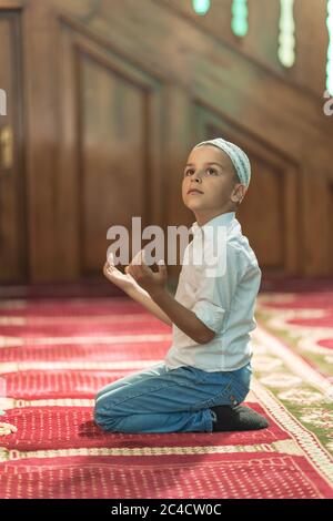 Un garçon prie dans la mosquée pendant le mois du Ramadan Banque D'Images