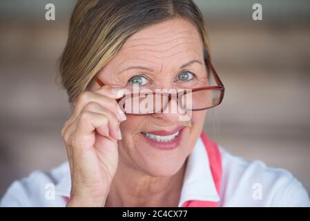 Potrait élégant attrayant mature femme d'affaires avec des lunettes et heureux expression sourire, arrière-plan flou. Banque D'Images