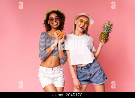 Deux filles Funky en vêtements d'été élégants posant avec des fruits exotiques frais Banque D'Images