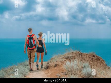 Vue arrière du concept Travel Lifestyle and Survival. Deux touristes marchant le long du chemin en haut de la colline le long de la mer sur une chaude journée d'été, un dos Banque D'Images