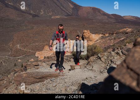 Groupe de jeunes adultes s'entraîner et courir ensemble à travers les sentiers sur la colline en plein air dans la nature. Banque D'Images