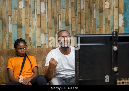 Couple afro-américain regardant un match à la télévision avec beaucoup d'enthousiasme Banque D'Images
