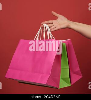 femme tient une pile de sacs en papier sur fond rouge, concept de shopping Banque D'Images