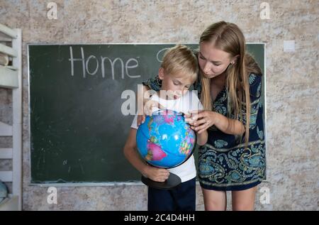 Mère étudie une carte du monde sur un globe avec son fils. Banque D'Images