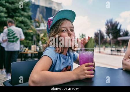 petite fille avec un cocktail à la table Banque D'Images