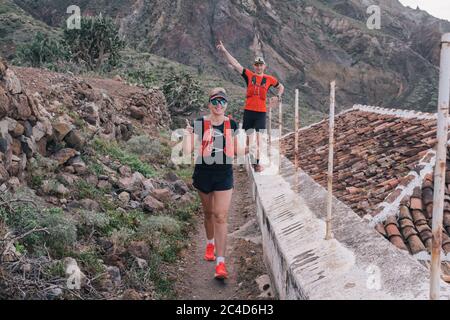 Groupe de jeunes adultes s'entraîner et courir ensemble à travers les sentiers sur la colline en plein air dans la nature. Banque D'Images