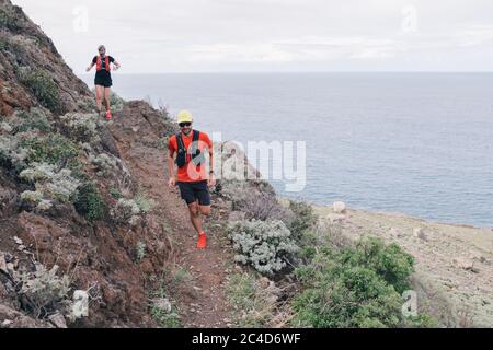 Groupe de jeunes adultes s'entraîner et courir ensemble à travers les sentiers sur la colline en plein air dans la nature. Banque D'Images