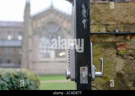 Point d'intérêt peu profond d'une porte de parc ouverte montrant un type numérique, serrure combinée, permettant aux membres du public d'accéder à une grande cathédrale. Banque D'Images