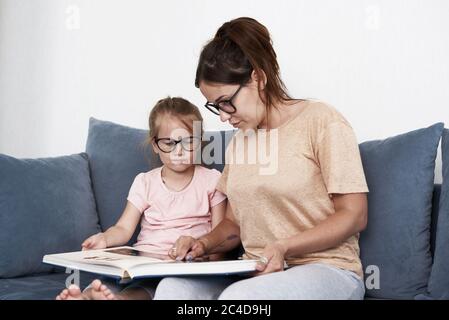 Mère et fille lisent un livre. Mère enseigne une petite fille. Banque D'Images