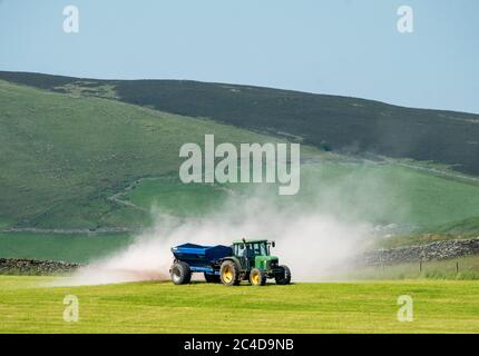 Tracteur et remorque qui épandent de la chaux sur un terrain de gazon près de Shankend, Hawick, aux frontières écossaises. Banque D'Images