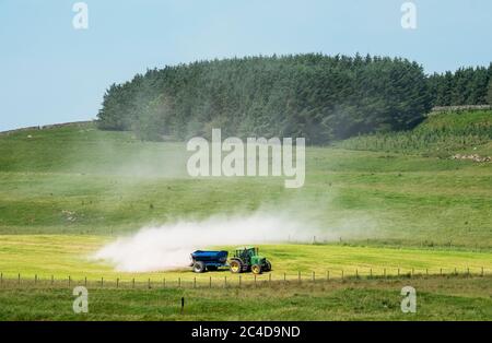 Tracteur et remorque qui épandent de la chaux sur un terrain de gazon près de Shankend, Hawick, aux frontières écossaises. Banque D'Images