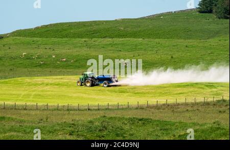 Tracteur et remorque qui épandent de la chaux sur un terrain de gazon près de Shankend, Hawick, aux frontières écossaises. Banque D'Images