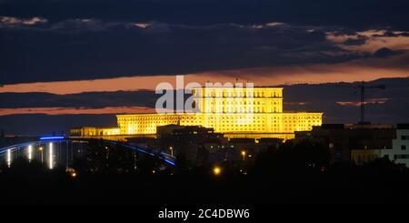 Le Palais du Parlement (Palatul Parlamentului en roumain) à Bucarest, Roumanie, illuminé la nuit, parmi les nuages sombres. Horizon de Bucarest, à Banque D'Images