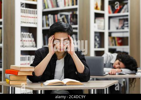 Deux étudiants fatigués étudiant dans la bibliothèque de l'université Banque D'Images