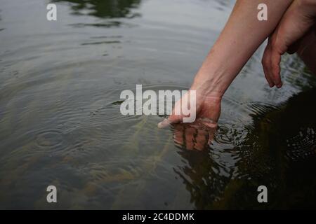 Mains trempant dans l'eau de la rivière Banque D'Images