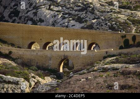 DWEJRA, GOZO, MALTE - 11 octobre 2014 : route de pont voûtée construite avec des pierres calcaires de la globigerina comme un aqueduc traversant la vallée et le lan de garigue Banque D'Images