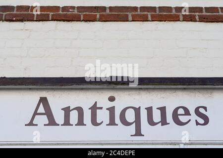 Vue rapprochée d'un panneau peint d'antiquités, vu sur un mur de briques blanchi à la chaux dans un village anglais. Banque D'Images