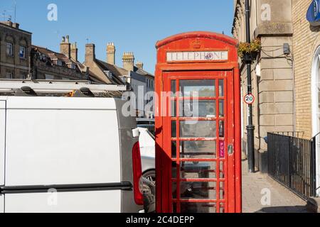 Une fourgonnette commerciale était garée très près d'une boîte téléphonique rouge traditionnelle dans une ville typiquement anglaise. Cette zone est fortement encombrée par les heures de travail. Banque D'Images