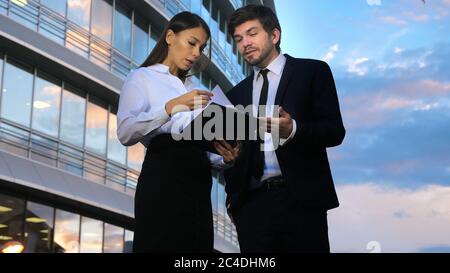 Les jeunes gens d'affaires parlent et visualisent des documents à l'extérieur. Banque D'Images