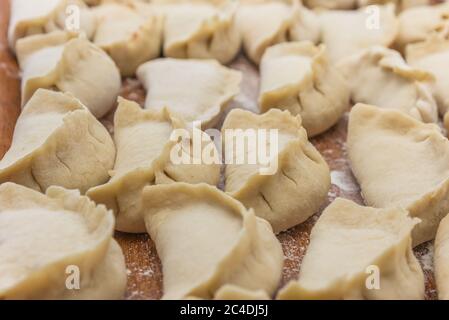Boulettes chinoises maison crues et non cuites sur une assiette en bois Banque D'Images