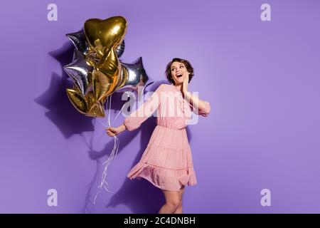 Portrait de mignon doux gai surprise fille impressionné par beaucoup de ballons en forme d'étoile elle obtient la victoire de la remise des diplômes gagner prix vêtements à pois Banque D'Images