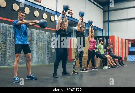 Les athlètes s'entraînent avec des kettlebells et font des squats Banque D'Images