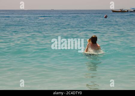Un jeune homme avec de longs cheveux blond émergeant de l'eau à Oludeniz, Turquie Banque D'Images