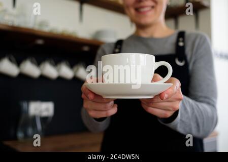 Femme serveuse avec une tasse souriante au café. Entreprise locale Banque D'Images
