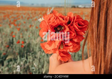 Mariée dans une robe blanche tenant un bouquet de fleurs de pavot, temps chaud de coucher de soleil sur le fond du champ de pavot rouge. Copier l'espace. Le concept de Banque D'Images