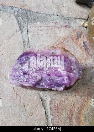 Gros plan d'une belle pierre améthyste sur un rocailleux sol pendant la lumière du jour Banque D'Images
